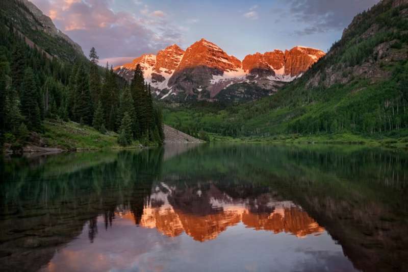 The morning Maroon Bells reflect a gorgeous sunrise in Maroon Bells Lake, one of the best natural wonders in Colorado