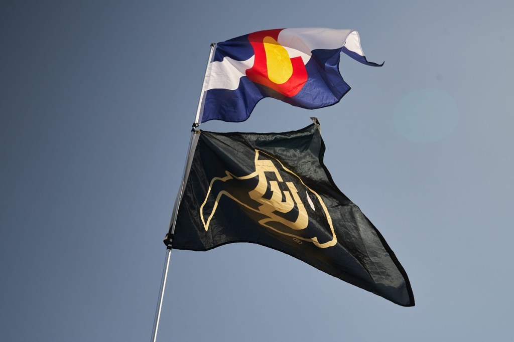 A University of Colorado flag flies below a state flag during a tailgate ahead of the Rocky Mountain Showdown in Fort Collins, Colo. on Sept. 14, 2024.